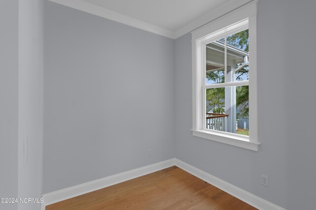 empty room with hardwood / wood-style flooring and crown molding