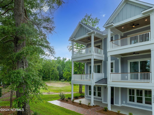 view of side of home with a yard, a balcony, and ceiling fan