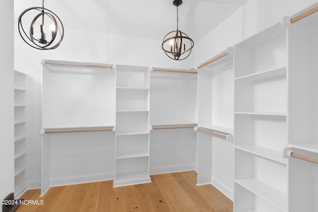 spacious closet with a notable chandelier and light wood-type flooring