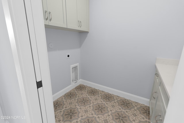 washroom with electric dryer hookup, cabinets, and light tile patterned floors