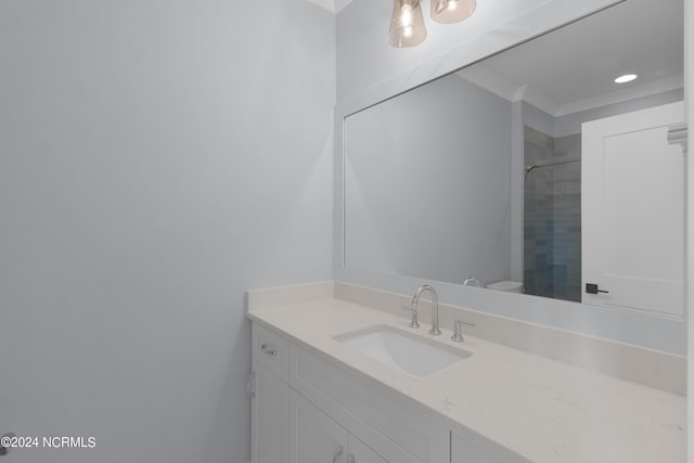 bathroom with a tile shower, vanity, and toilet