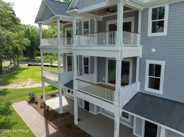 back of property with ceiling fan, a balcony, and a lawn