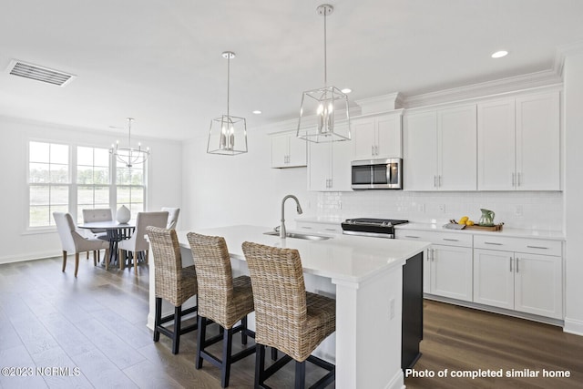 kitchen featuring visible vents, appliances with stainless steel finishes, dark wood finished floors, and a sink