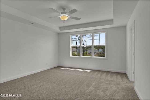 unfurnished room featuring a ceiling fan, a tray ceiling, baseboards, and carpet