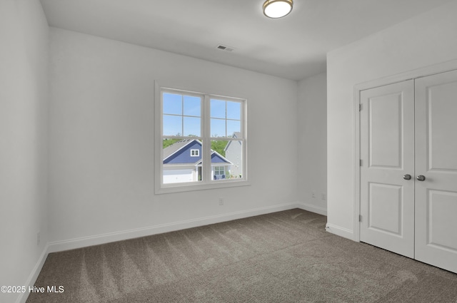unfurnished bedroom featuring baseboards, carpet, visible vents, and a closet