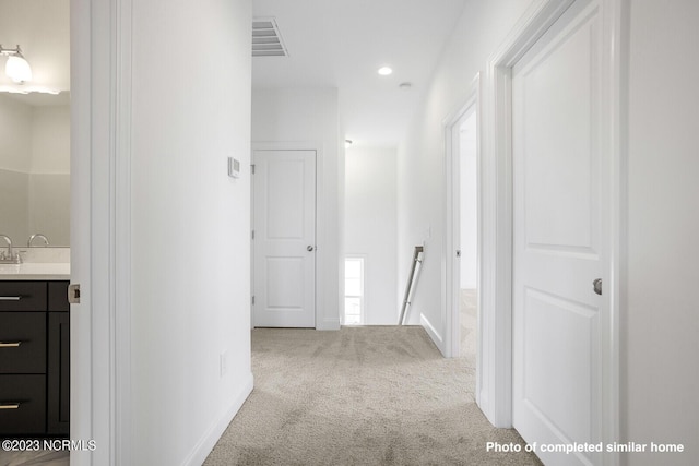 hall featuring carpet floors, baseboards, visible vents, and an upstairs landing