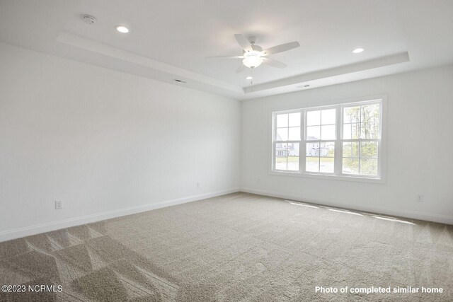 unfurnished room with a tray ceiling, carpet flooring, baseboards, and recessed lighting