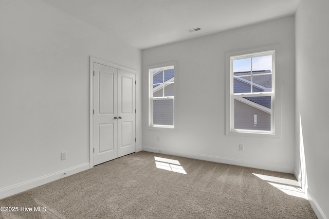 spare room featuring visible vents, carpet flooring, and baseboards