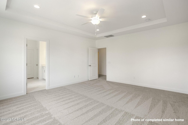 spare room featuring baseboards, visible vents, a raised ceiling, carpet floors, and recessed lighting