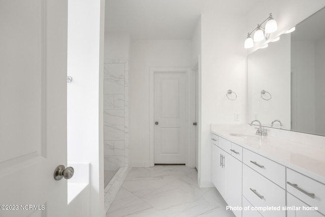 bathroom featuring marble finish floor, a tile shower, and vanity