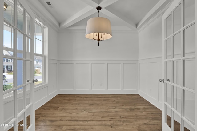 unfurnished dining area featuring french doors, a decorative wall, beam ceiling, and visible vents