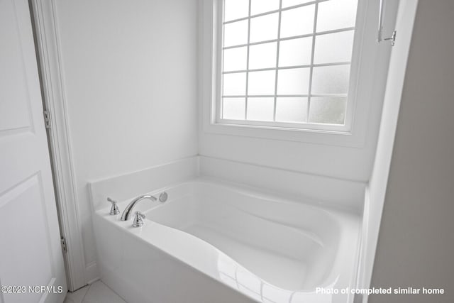 bathroom featuring a spacious closet, baseboards, and a tile shower