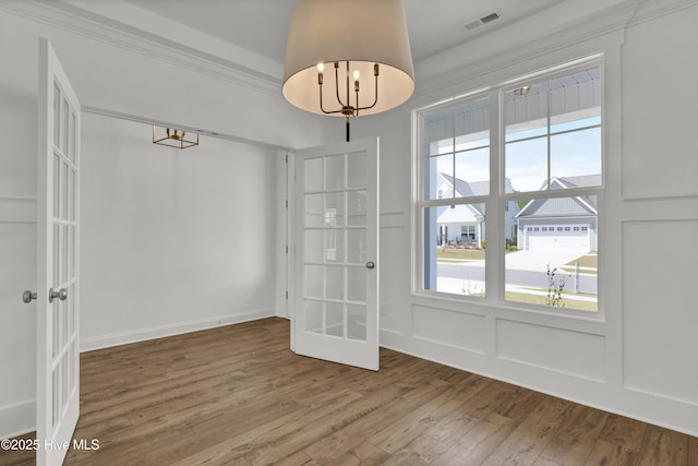 unfurnished dining area with french doors, wood finished floors, visible vents, and an inviting chandelier