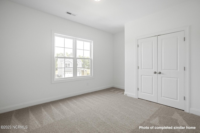 unfurnished bedroom with carpet floors, baseboards, visible vents, and a closet