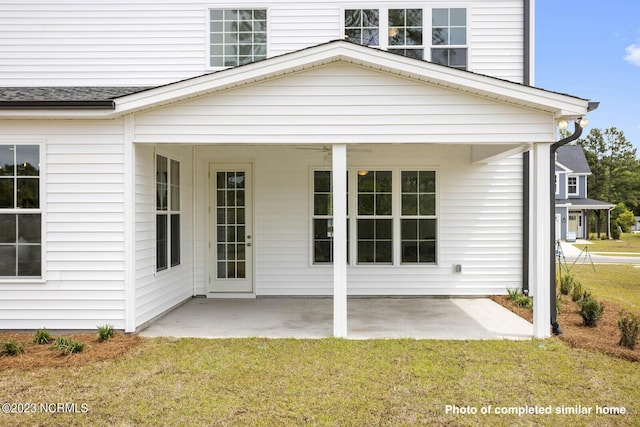 doorway to property featuring a patio, roof with shingles, and a lawn