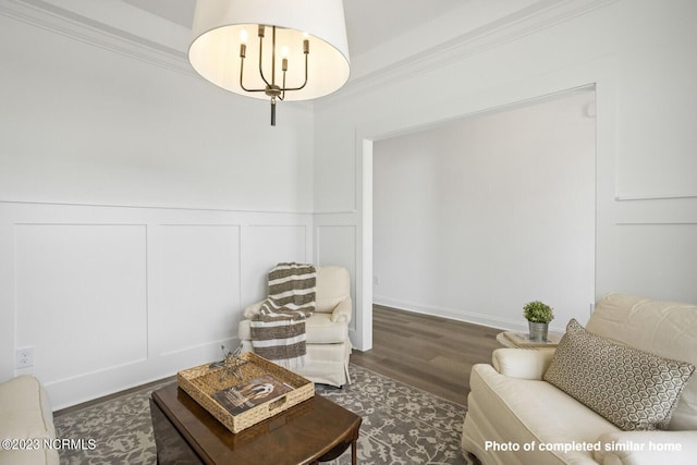 sitting room featuring a chandelier, a decorative wall, crown molding, and wood finished floors