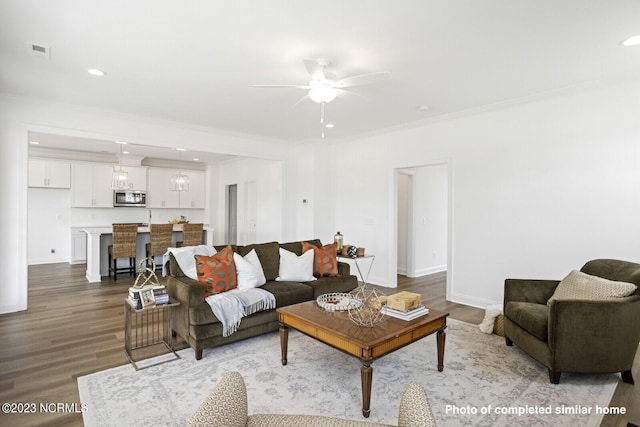 living room with visible vents, crown molding, and wood finished floors