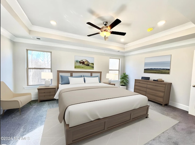 carpeted bedroom with multiple windows, ceiling fan, and a raised ceiling