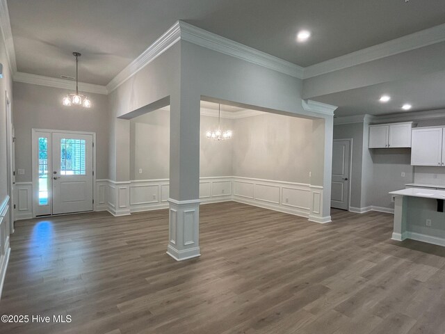 1114 Natal Dr SE, Bolivia, NC 28422 - unfurnished living room with a chandelier, a decorative wall, ornamental molding, dark wood-type flooring, and wainscoting