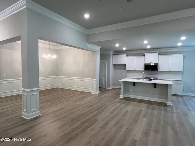 1114 Natal Dr SE, Bolivia, NC 28422 - kitchen with stainless steel microwave, crown molding, white cabinets, light countertops, and dark wood-style floors