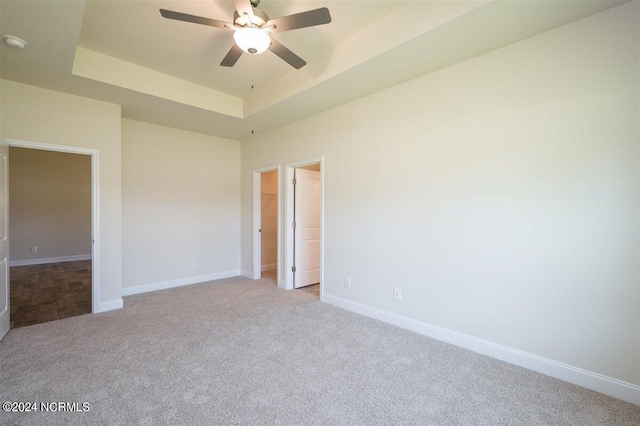 carpeted spare room with ceiling fan and a raised ceiling