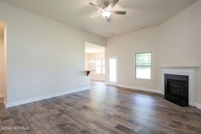 unfurnished living room featuring dark wood-type flooring and ceiling fan with notable chandelier