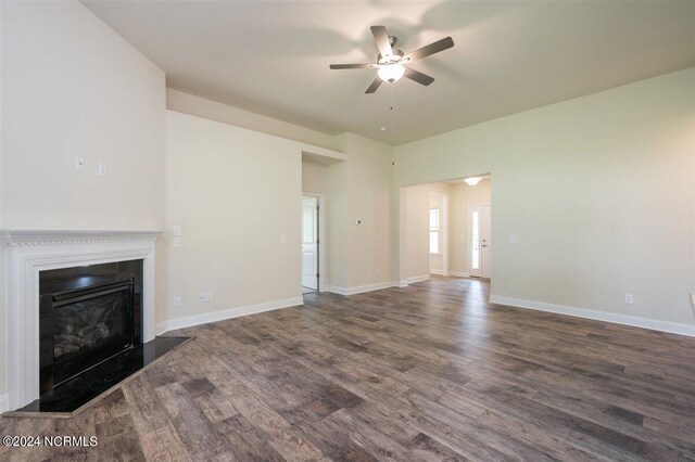 unfurnished living room with ceiling fan, baseboards, a glass covered fireplace, and wood finished floors
