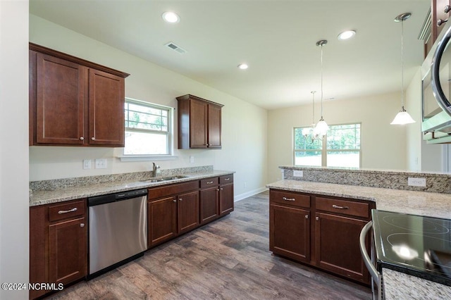 kitchen with light stone counters, hanging light fixtures, sink, appliances with stainless steel finishes, and dark hardwood / wood-style floors