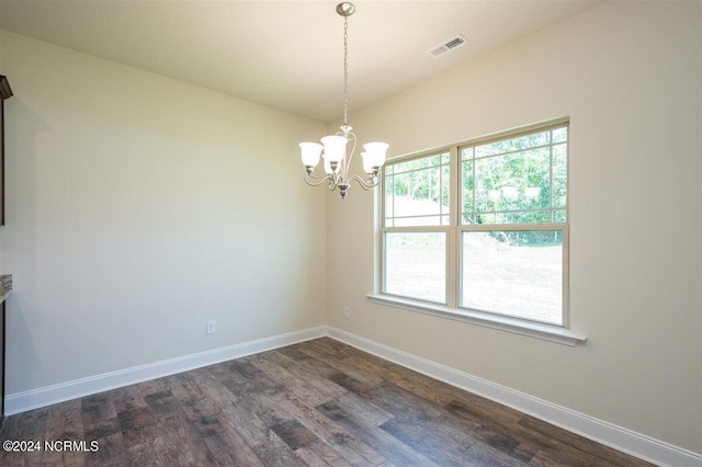 empty room featuring baseboards, a chandelier, dark wood-type flooring, and visible vents