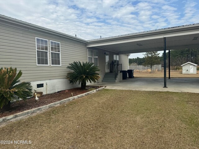 exterior space with a shed, a carport, and a lawn