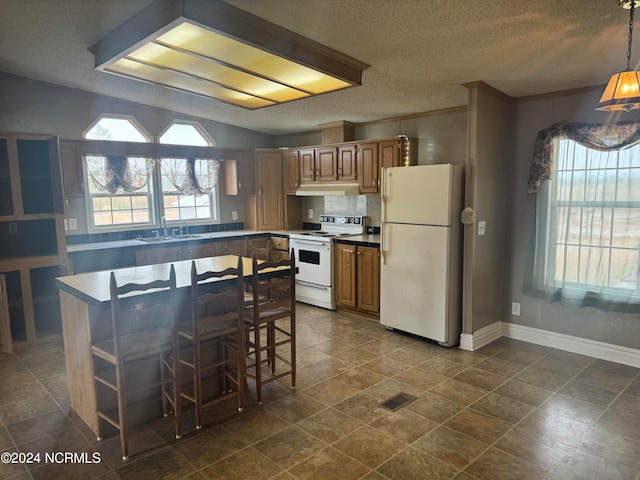 kitchen with pendant lighting, dark tile floors, white appliances, and sink