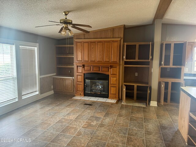 unfurnished living room featuring a textured ceiling, dark tile floors, and ceiling fan