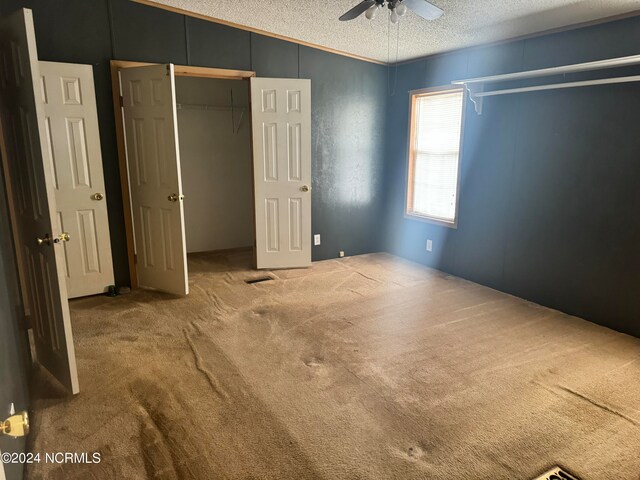 unfurnished bedroom with light carpet, a textured ceiling, and ceiling fan