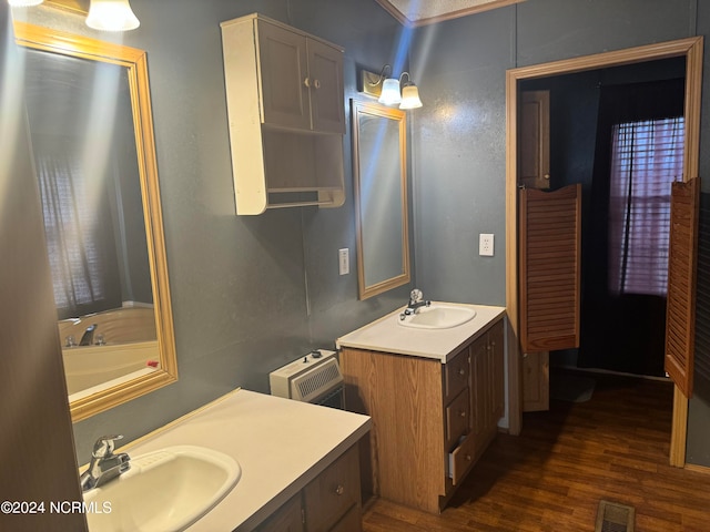 bathroom featuring crown molding, hardwood / wood-style floors, a washtub, and vanity