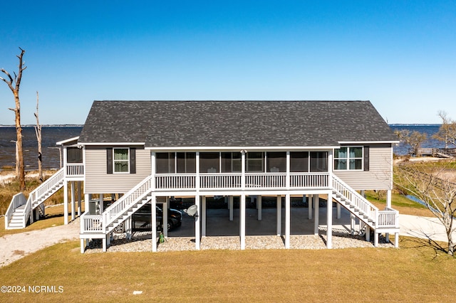 rear view of property with a yard, a sunroom, and a water view