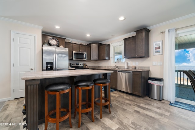 kitchen with stainless steel appliances, a healthy amount of sunlight, dark brown cabinetry, and a center island