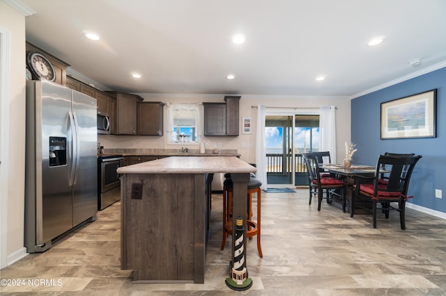 kitchen featuring appliances with stainless steel finishes, dark brown cabinets, plenty of natural light, and a kitchen island