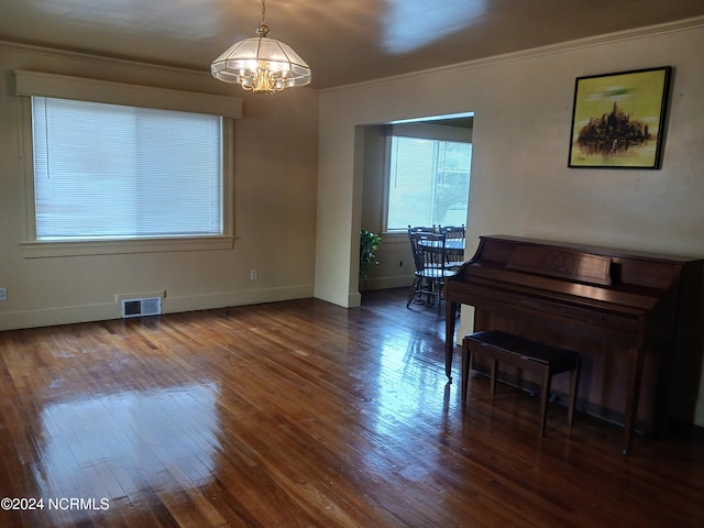 miscellaneous room featuring a chandelier, crown molding, and dark wood-type flooring