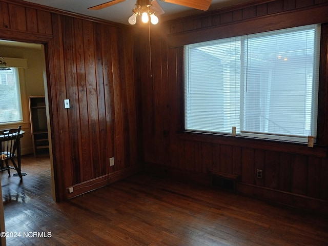 spare room featuring wooden walls, ceiling fan, and dark hardwood / wood-style floors