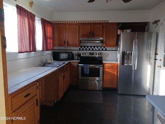 kitchen featuring stainless steel appliances, ceiling fan, backsplash, tile counters, and sink