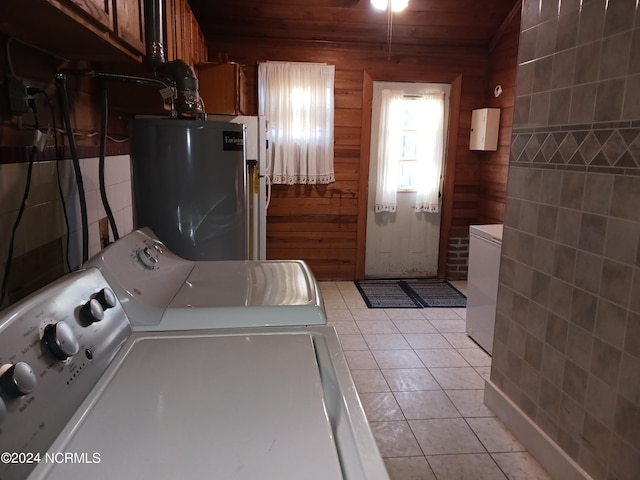 clothes washing area with wooden walls, light tile floors, wooden ceiling, separate washer and dryer, and water heater