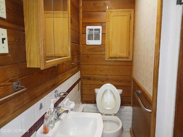 bathroom with wood walls, toilet, and sink