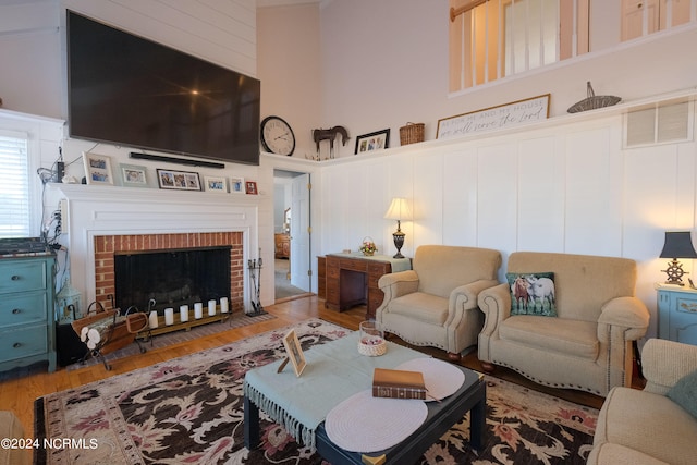 living room featuring a towering ceiling, a fireplace, and hardwood / wood-style floors