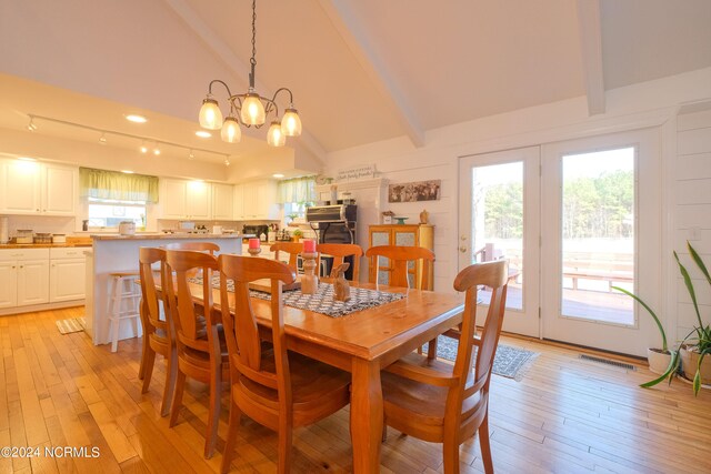 dining space featuring a chandelier, light hardwood / wood-style floors, rail lighting, and beamed ceiling