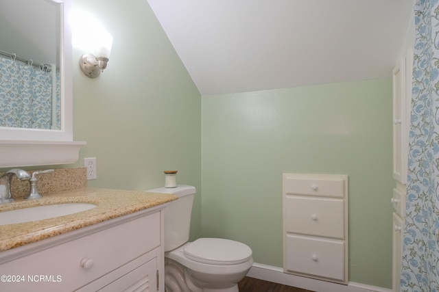 bathroom with oversized vanity, toilet, vaulted ceiling, and hardwood / wood-style floors