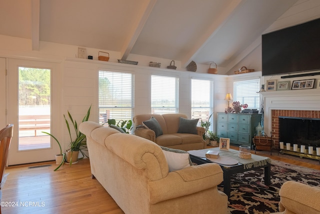 living room with beamed ceiling, light hardwood / wood-style floors, high vaulted ceiling, and a fireplace