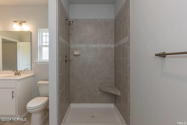 bathroom with vanity, tiled shower, tile patterned floors, and toilet