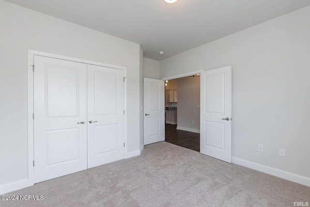 unfurnished bedroom with dark carpet and a closet