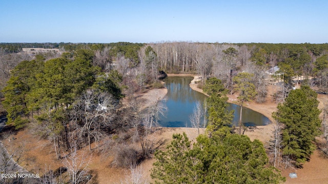 drone / aerial view of a nearby body of water and a heavily wooded area