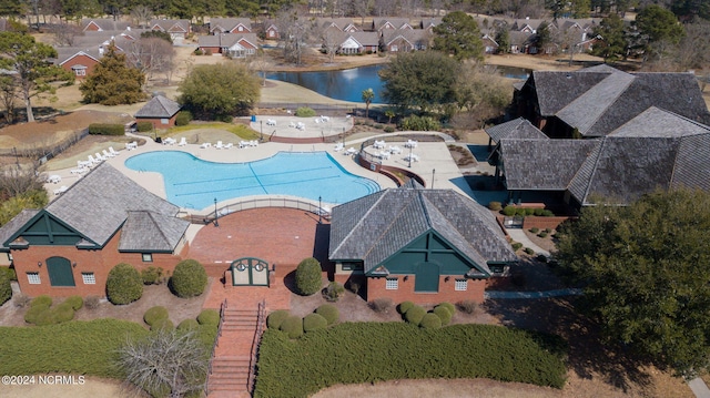 aerial perspective of suburban area featuring a pool and a nearby body of water